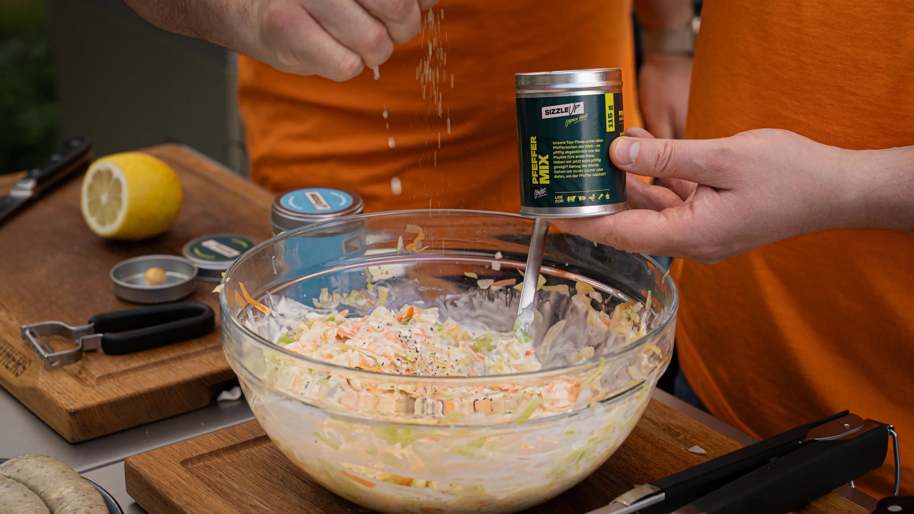 Person würzt eine Schüssel Krautsalat aus der Dose, während eine weitere Person umrührt.