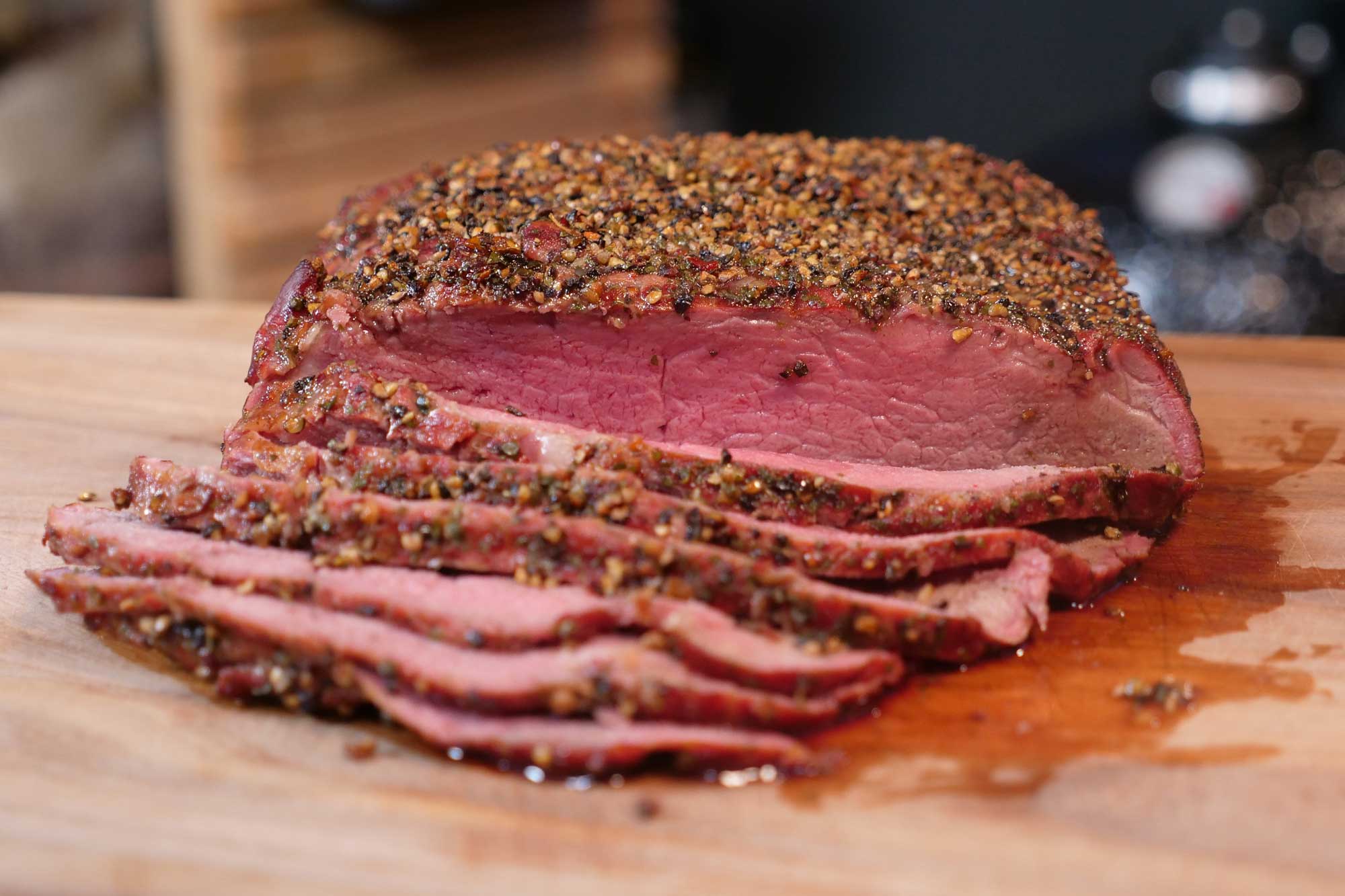 Geschnittenes, gewürztes Rindfleisch auf einem Holzbrett, rosa und saftig.