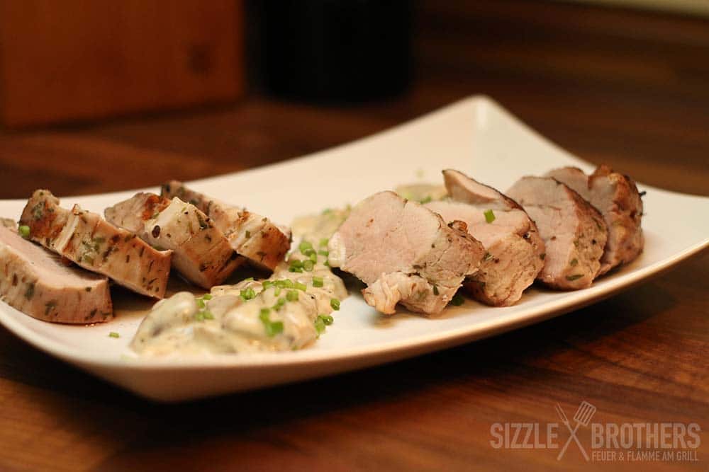 Geschnittenes Filet auf einem weißen Teller mit Soße und Schnittlauch.