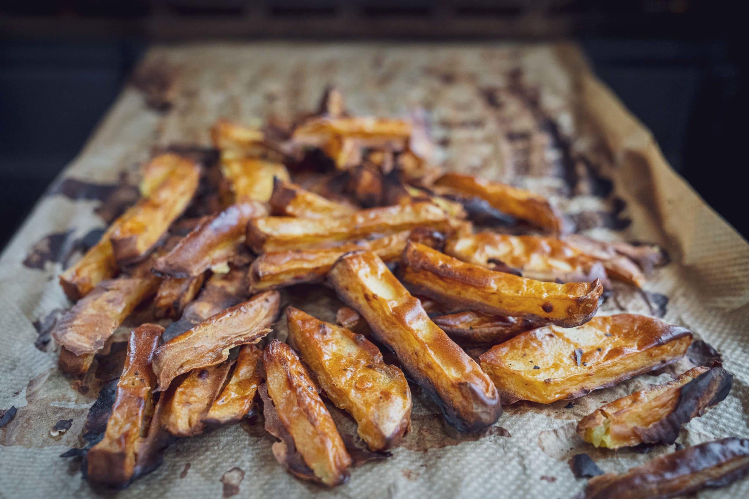 Krosse Pommes frites auf Backpapier, frisch aus dem Ofen.