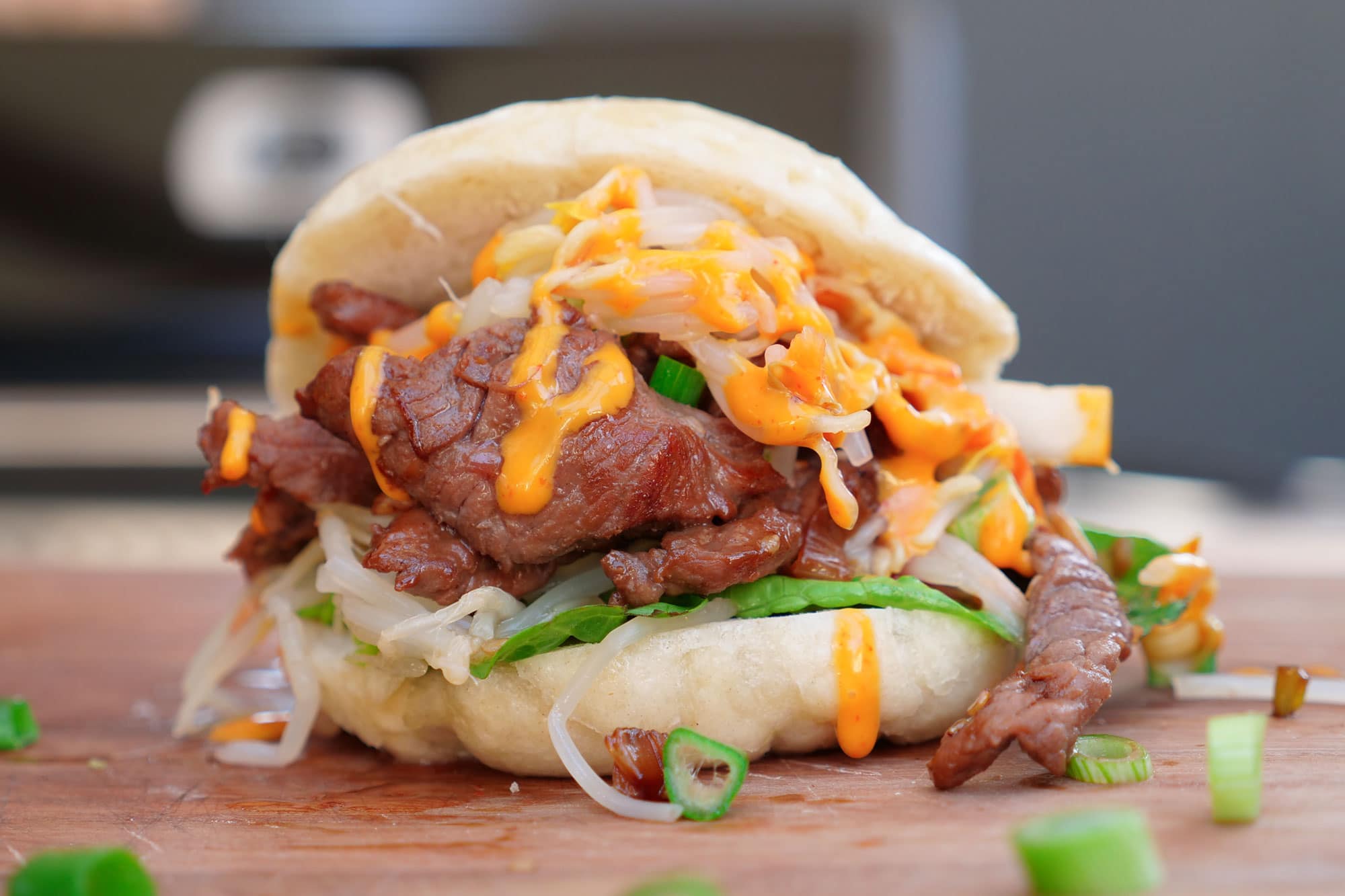 Gedämpfter Bun gefüllt mit Rindfleisch, Zwiebeln und orangefarbener Sauce.