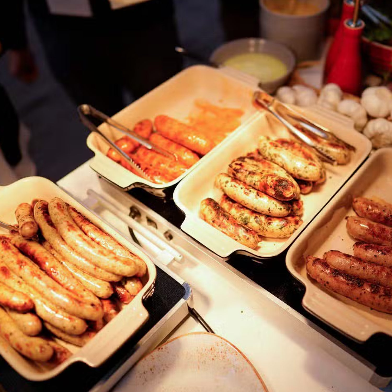 Gebratene Würste und Paprika in Keramikschalen nebeneinander.