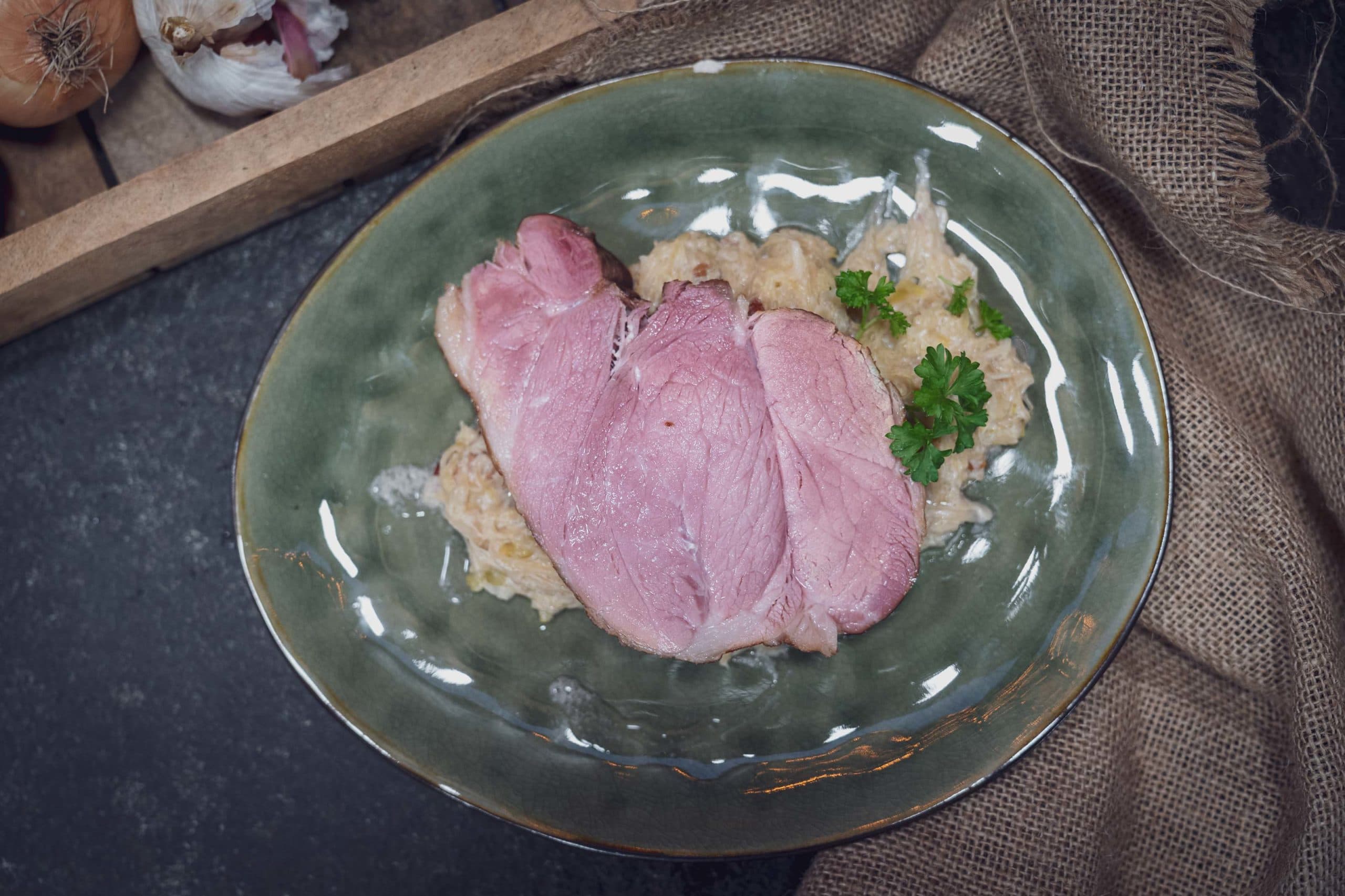 Zwei Scheiben Kassler auf Kartoffelpüree, garniert mit Petersilie.