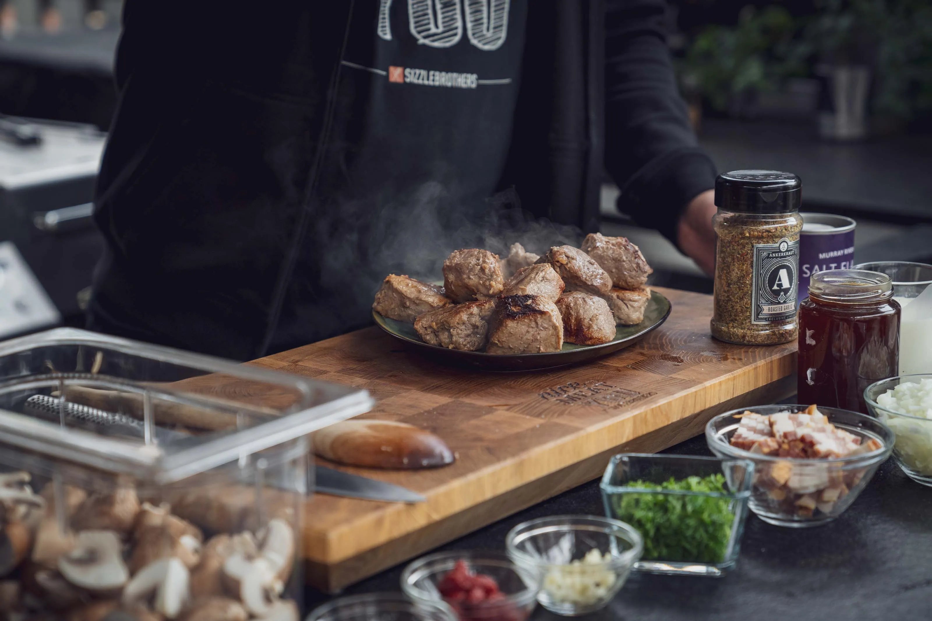Dampfwarmes Fleisch auf Teller vor einem Koch in der Küche.