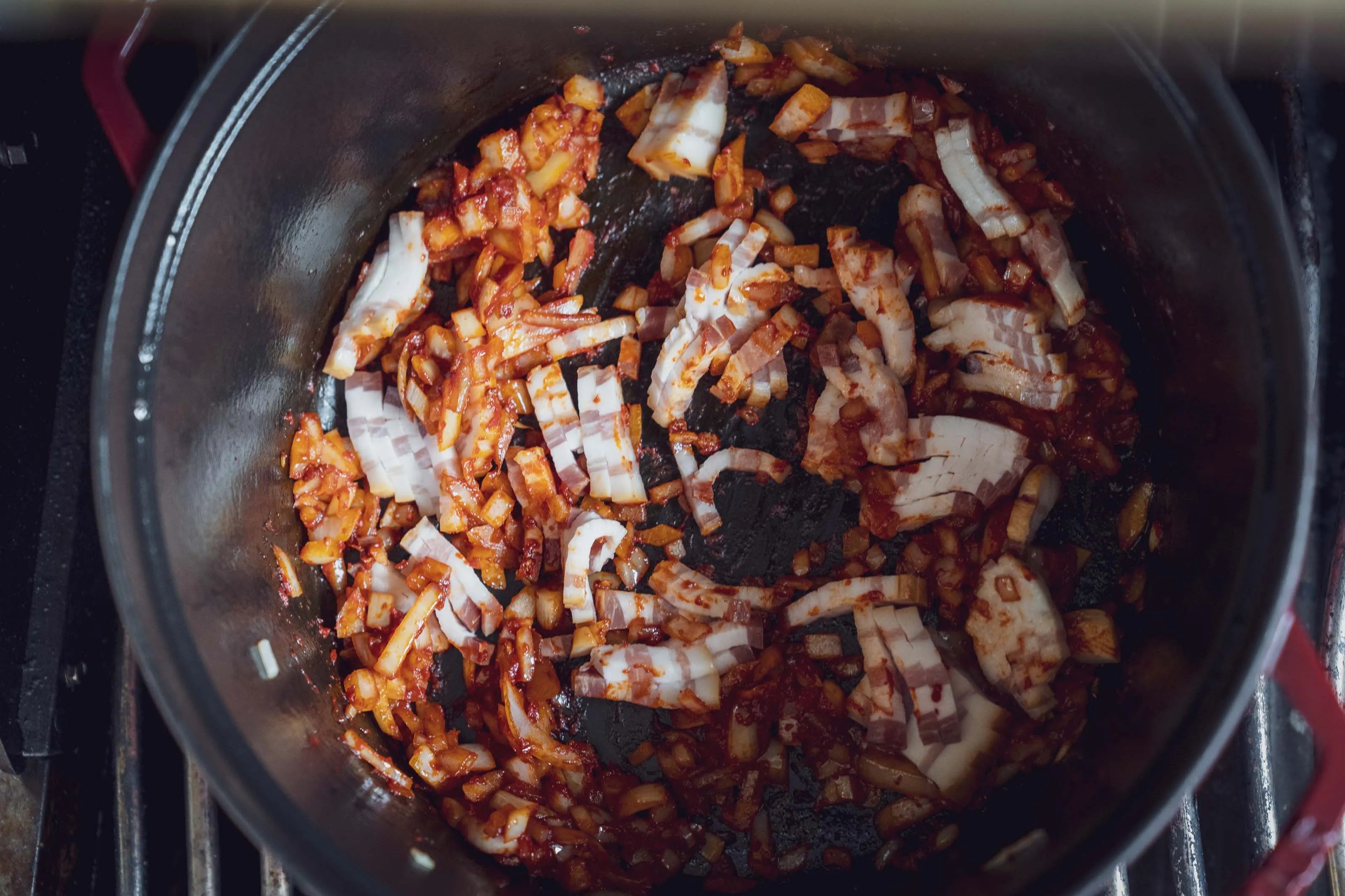 Topf mit Zwiebeln und Paprika auf dem Herd.