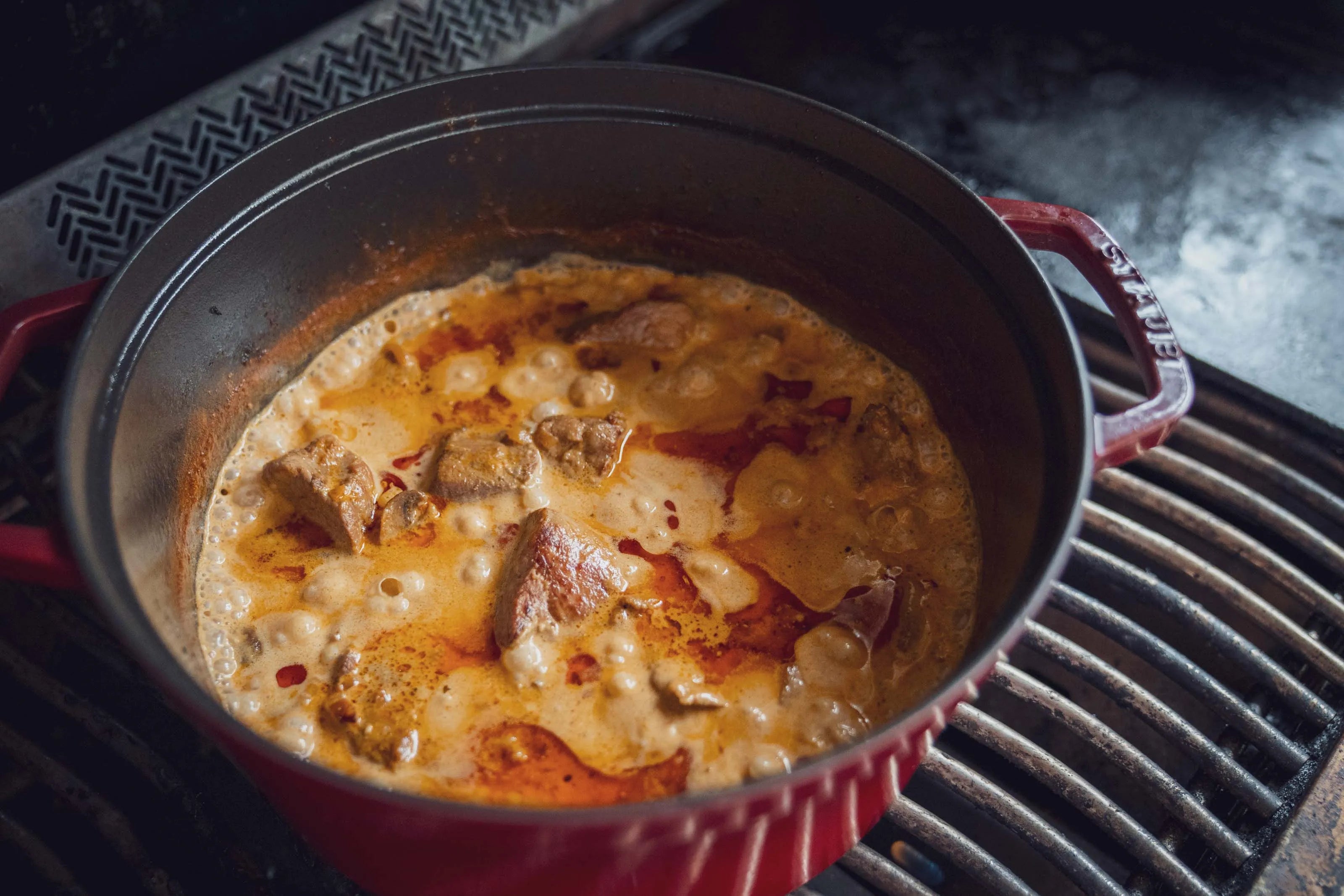 Roter Topf auf Herd mit köchelndem Eintopf.