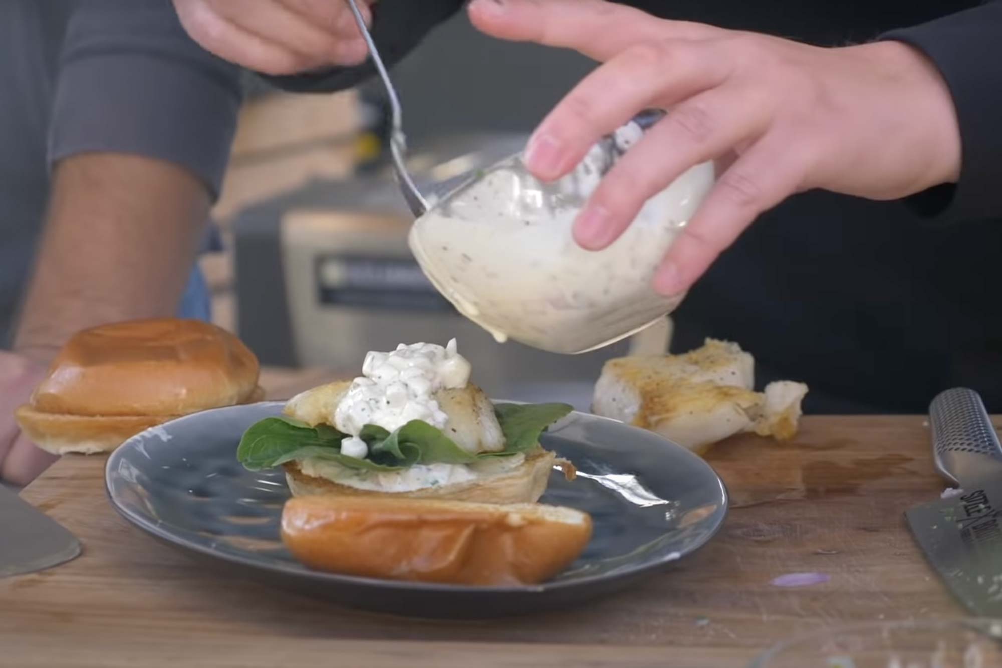 Fischburger wird mit Remoulade belegt