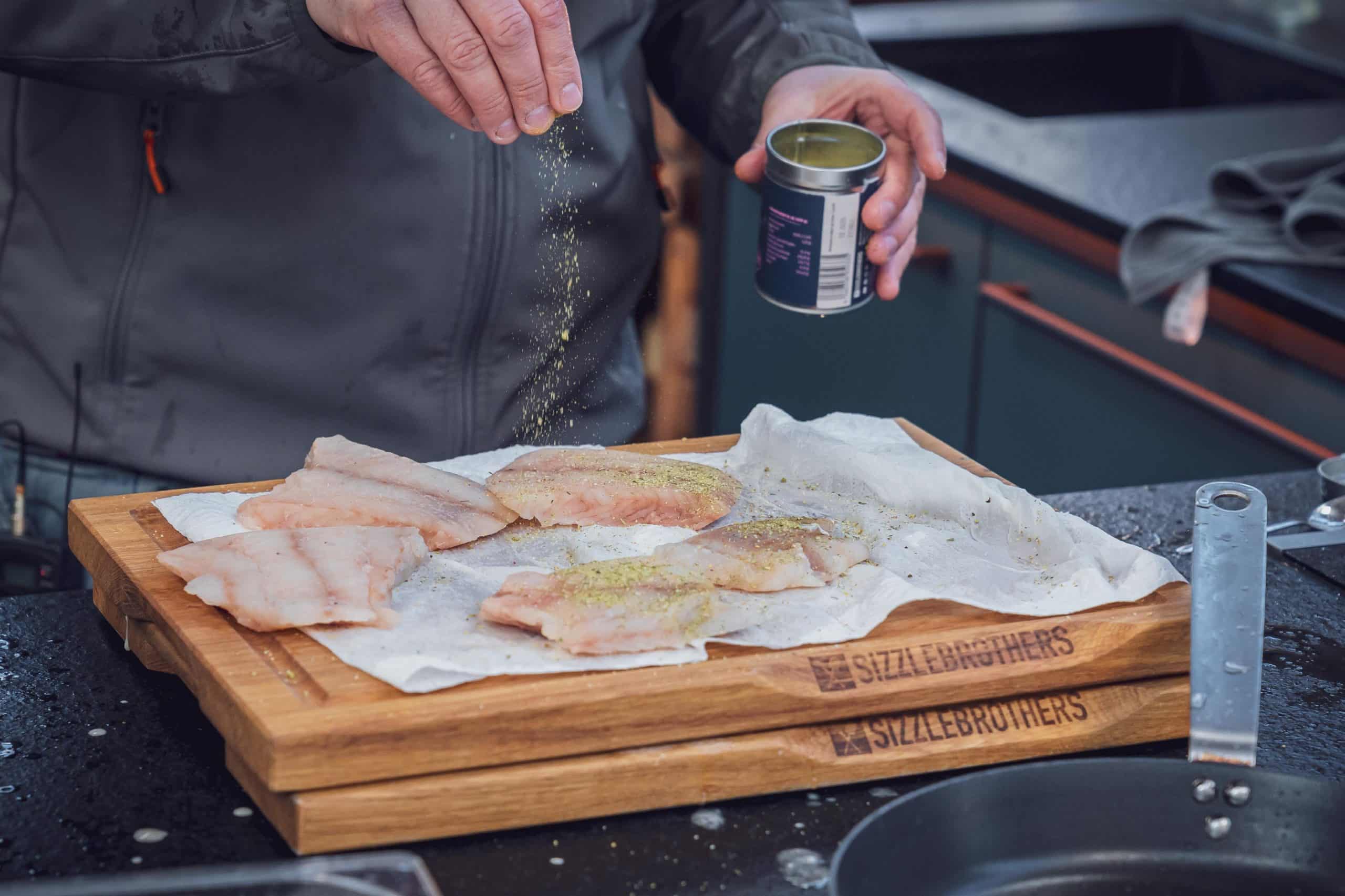 Fischfilets für Fish and Chips werden mit Lachsgewürz gewürzt