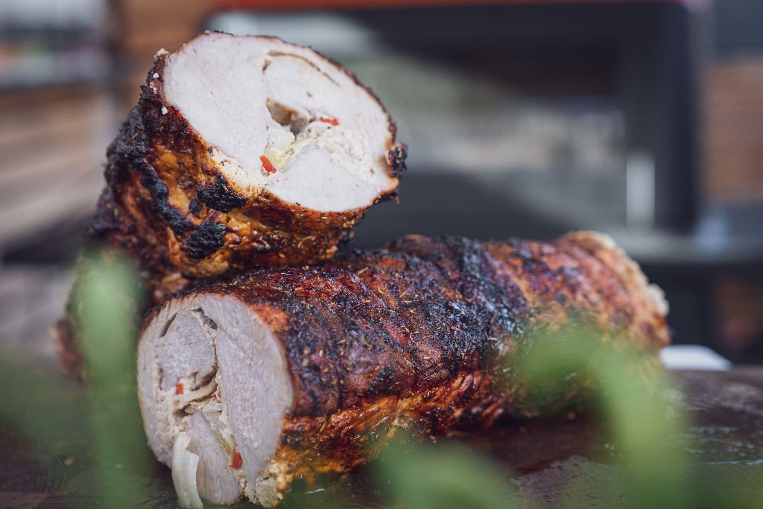 Zwei Stücke gerollter Schweinebraten mit knuspriger Kräuterkruste.