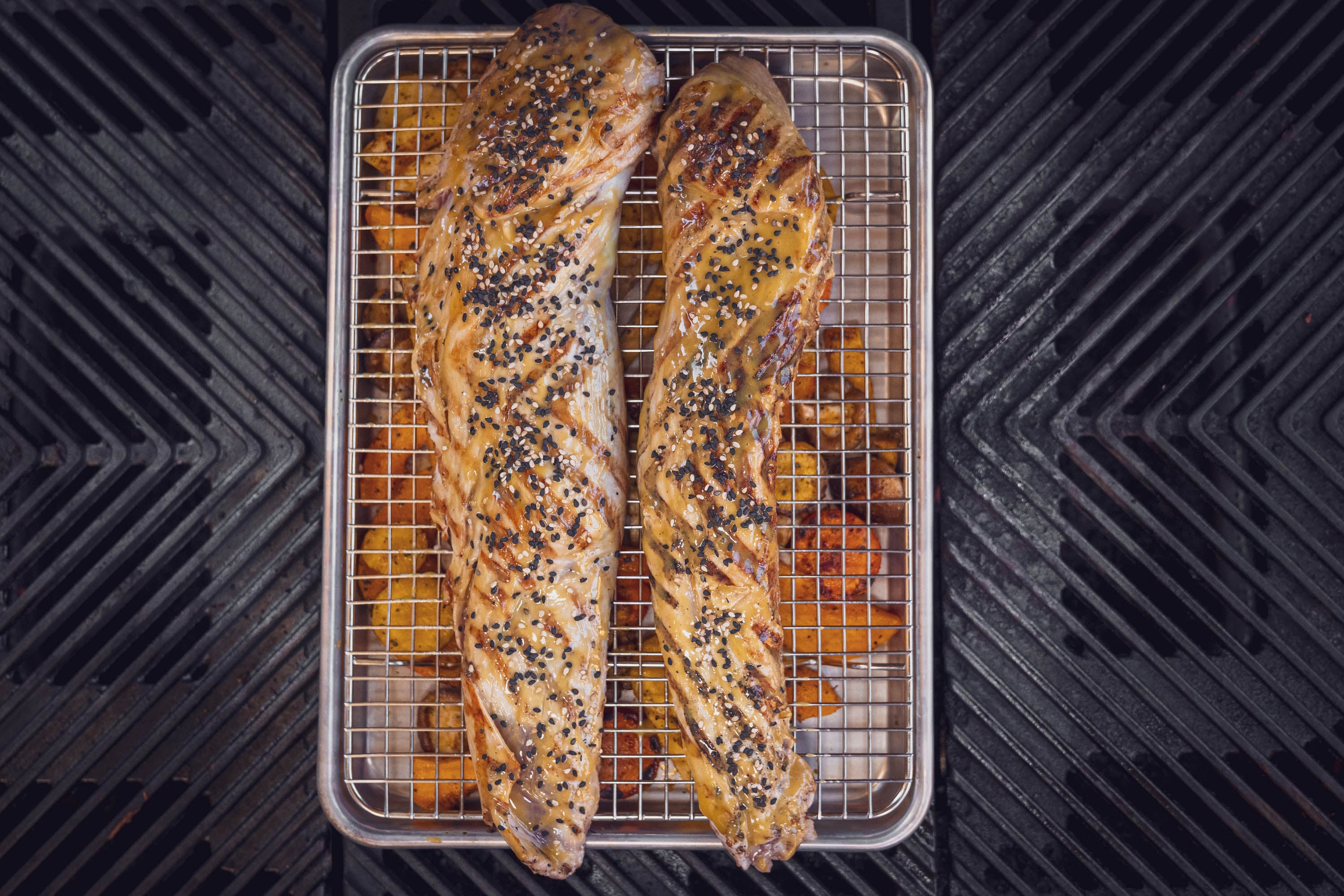 Das Schweinefilet liegt mit dem Grillgemüse auf dem Grill