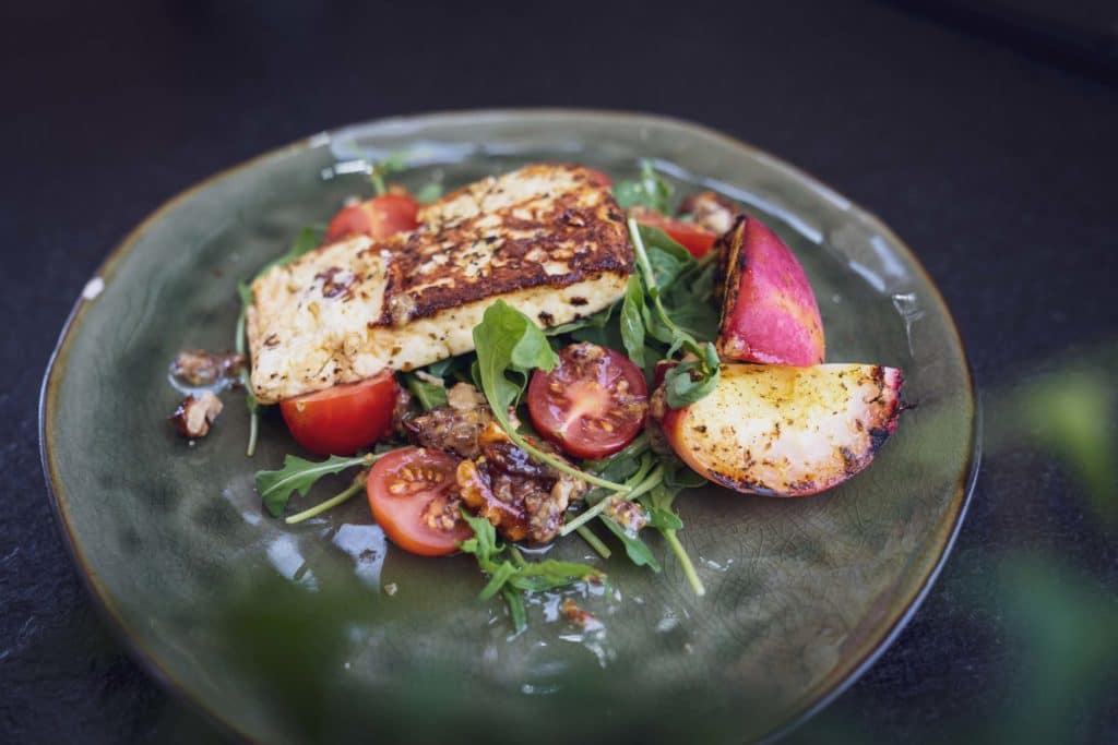 Grüner Teller mit gegrilltem Gemüse, Tomaten und Kräutern.