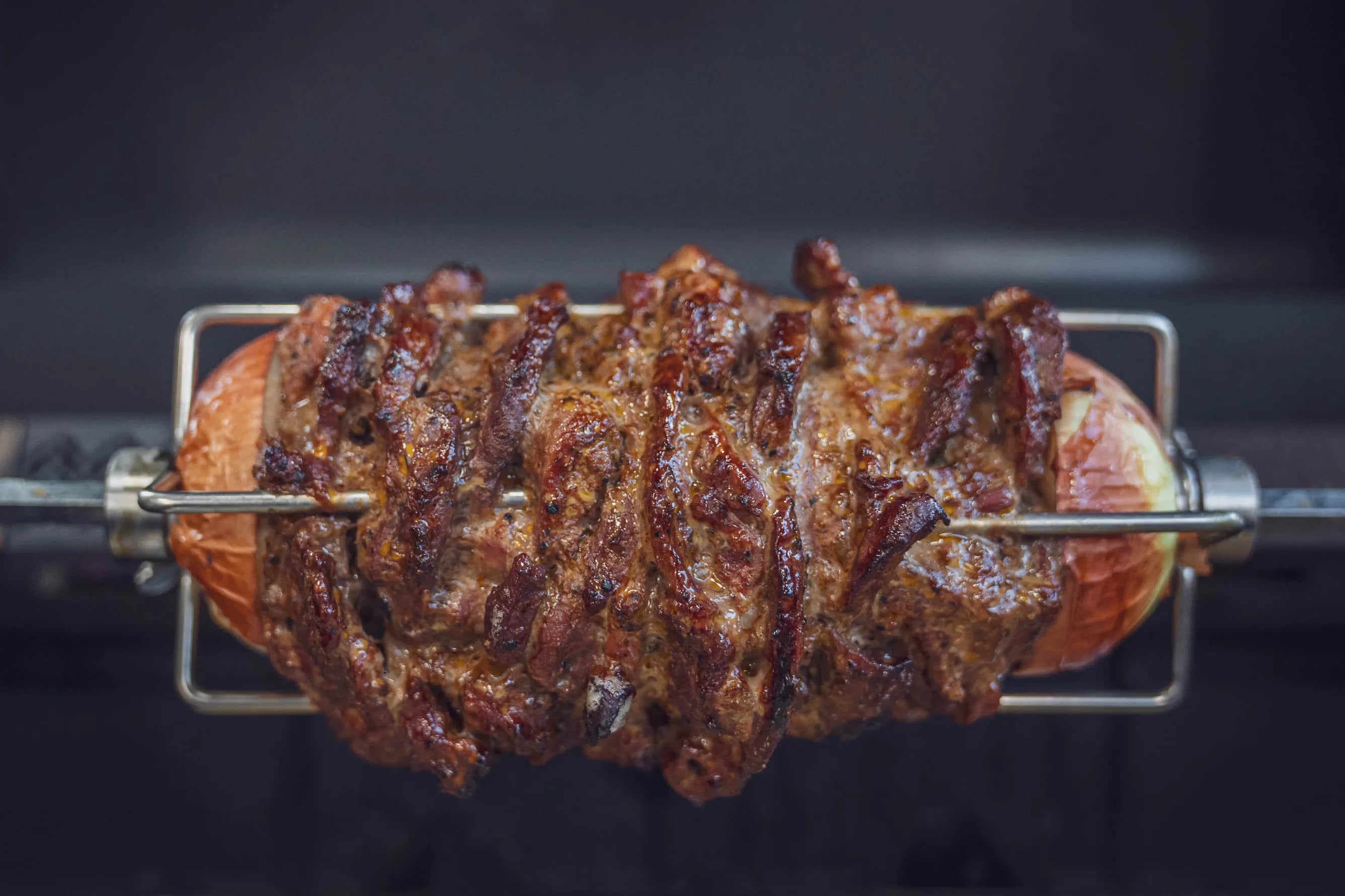 Ein großes Stück Braten auf einem Drehspieß, gleichmäßig gebräunt.