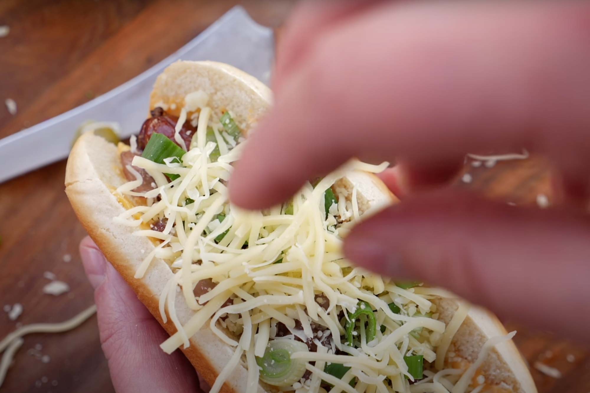 Käse wird über das Brötchen gegeben