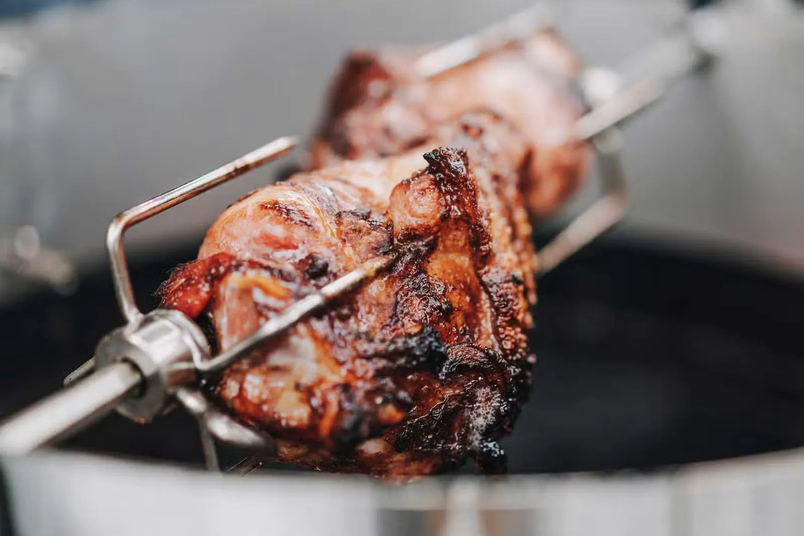 Gegrilltes Fleisch auf einem Drehspieß über schwarzem Hintergrund.