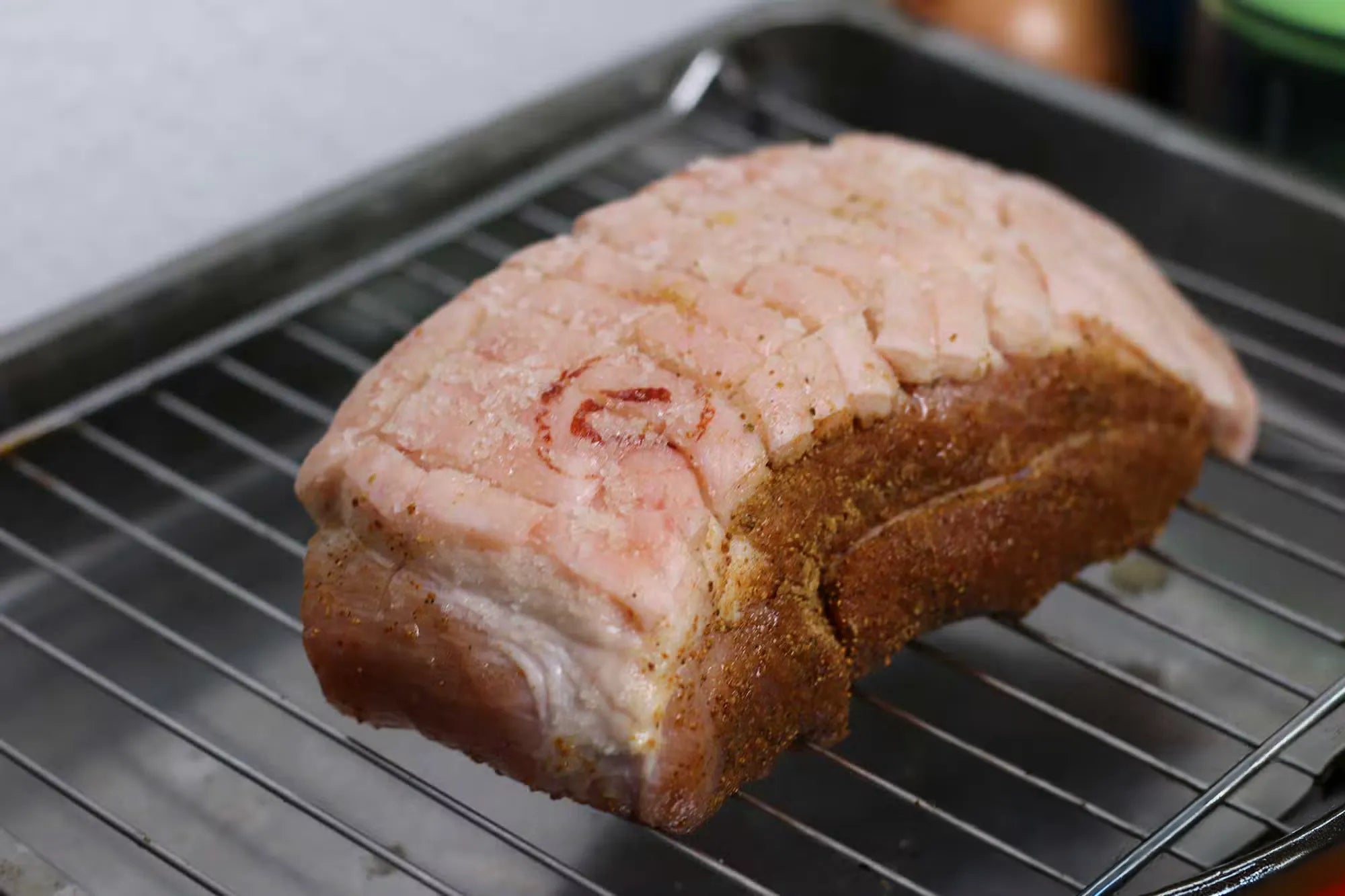 Ein Stück gewürzter Schweinebraten auf einem Rost im Ofen.