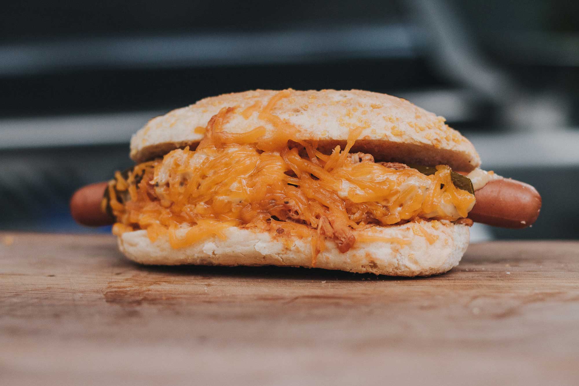 Hotdog in Brötchen, bedeckt mit geschmolzenem Cheddar.