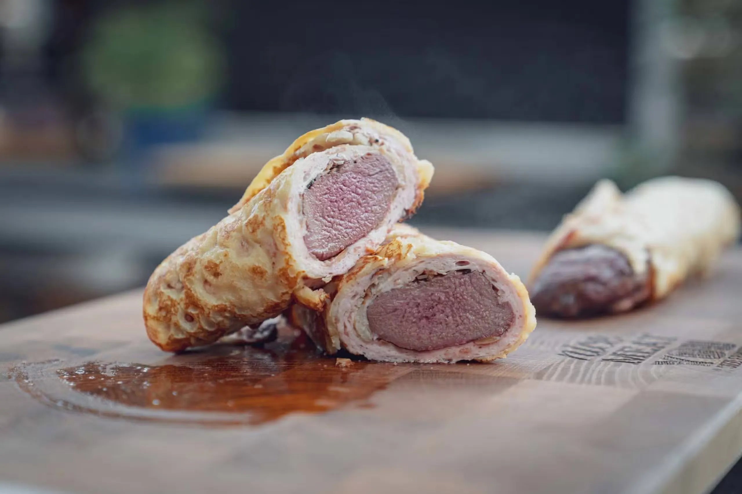 Aufgeschnittene Beef-Wellington-Rolle auf Holzbrett.