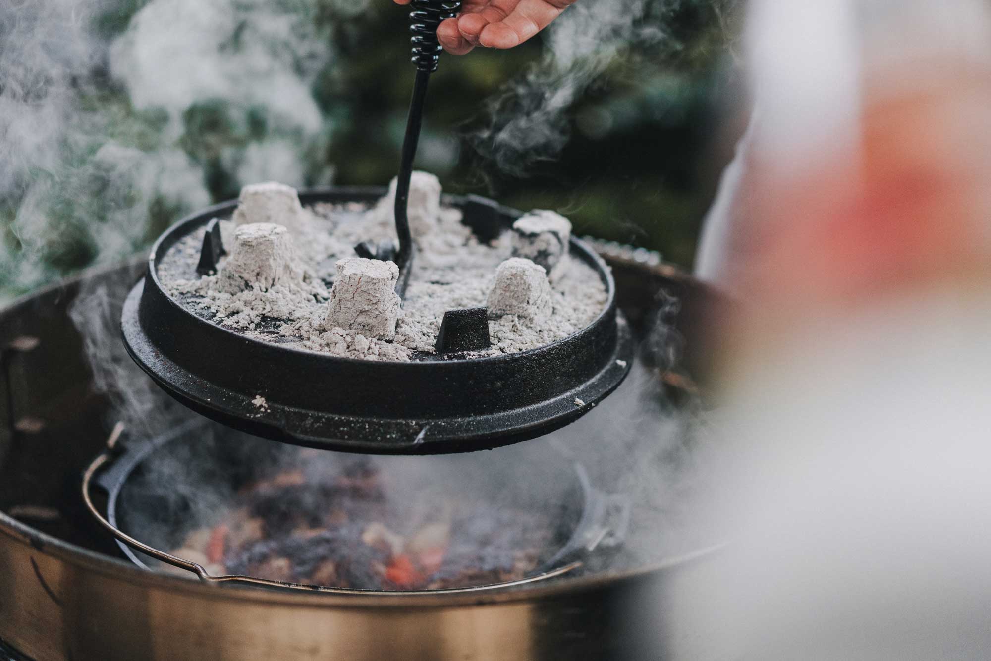 Der Deckel des Dutch Ovens wird angehoben, um die Rippchen darin anzuschauen