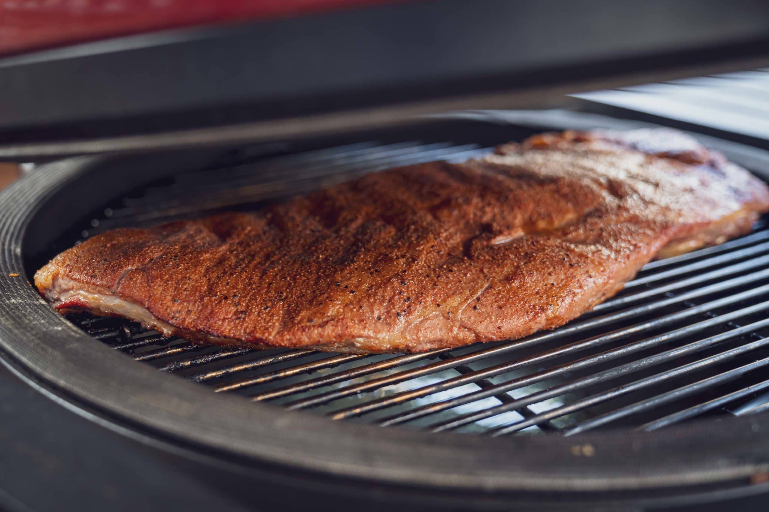 Großes, gebräuntes Stück Fleisch auf einem Grillrost.