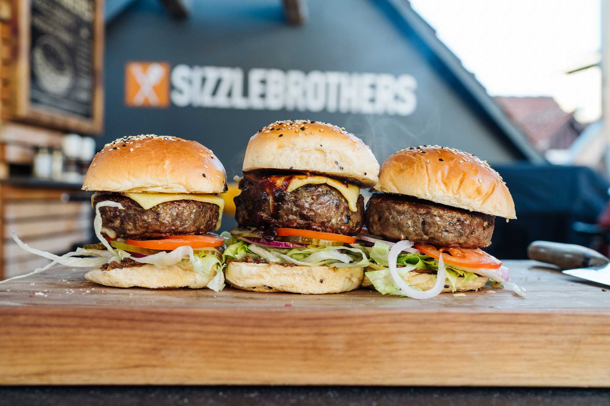 3 Stuffed Cheeseburger stehen auf einem großen Holzbrett