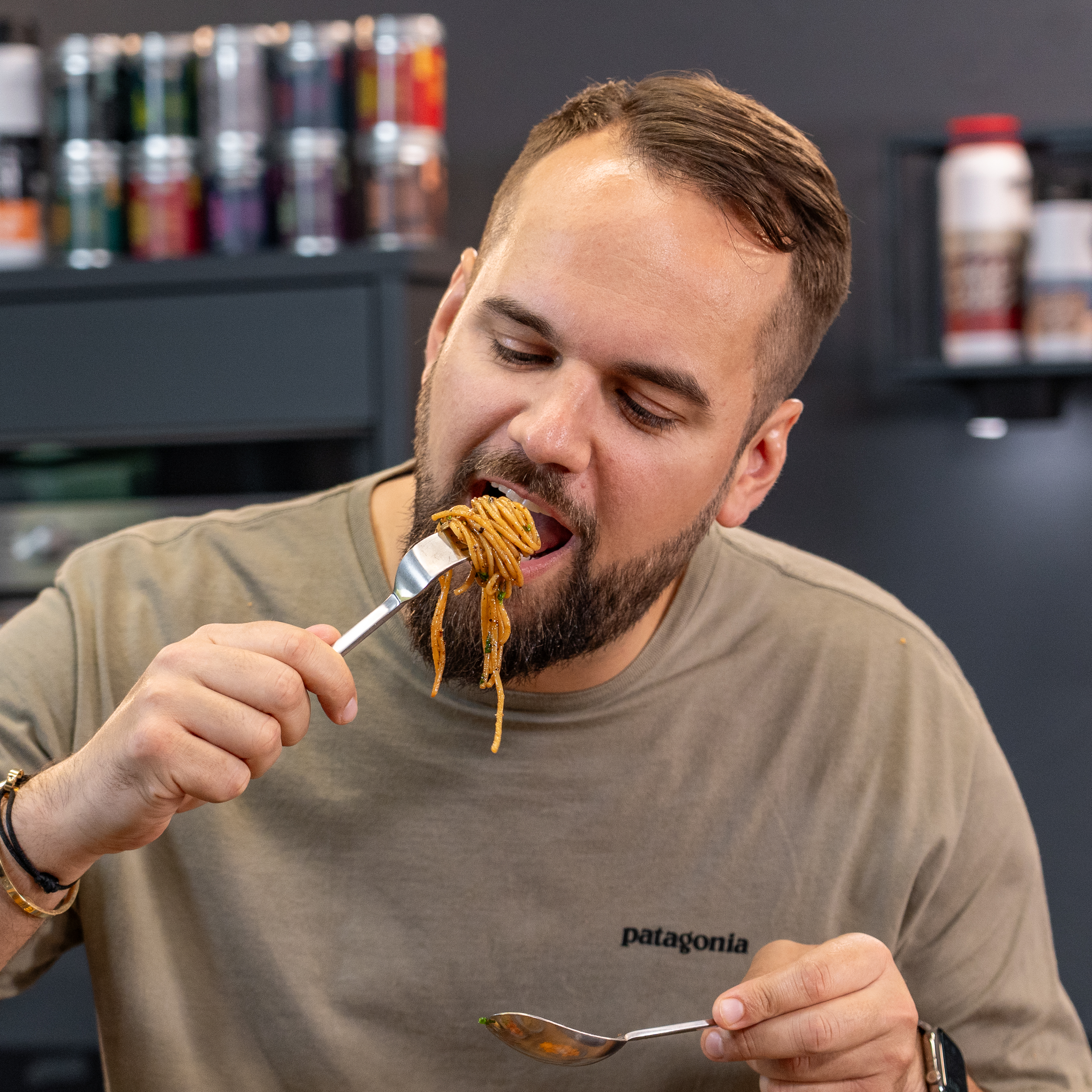 Person isst Spaghetti mit einer Gabel in der Küche.