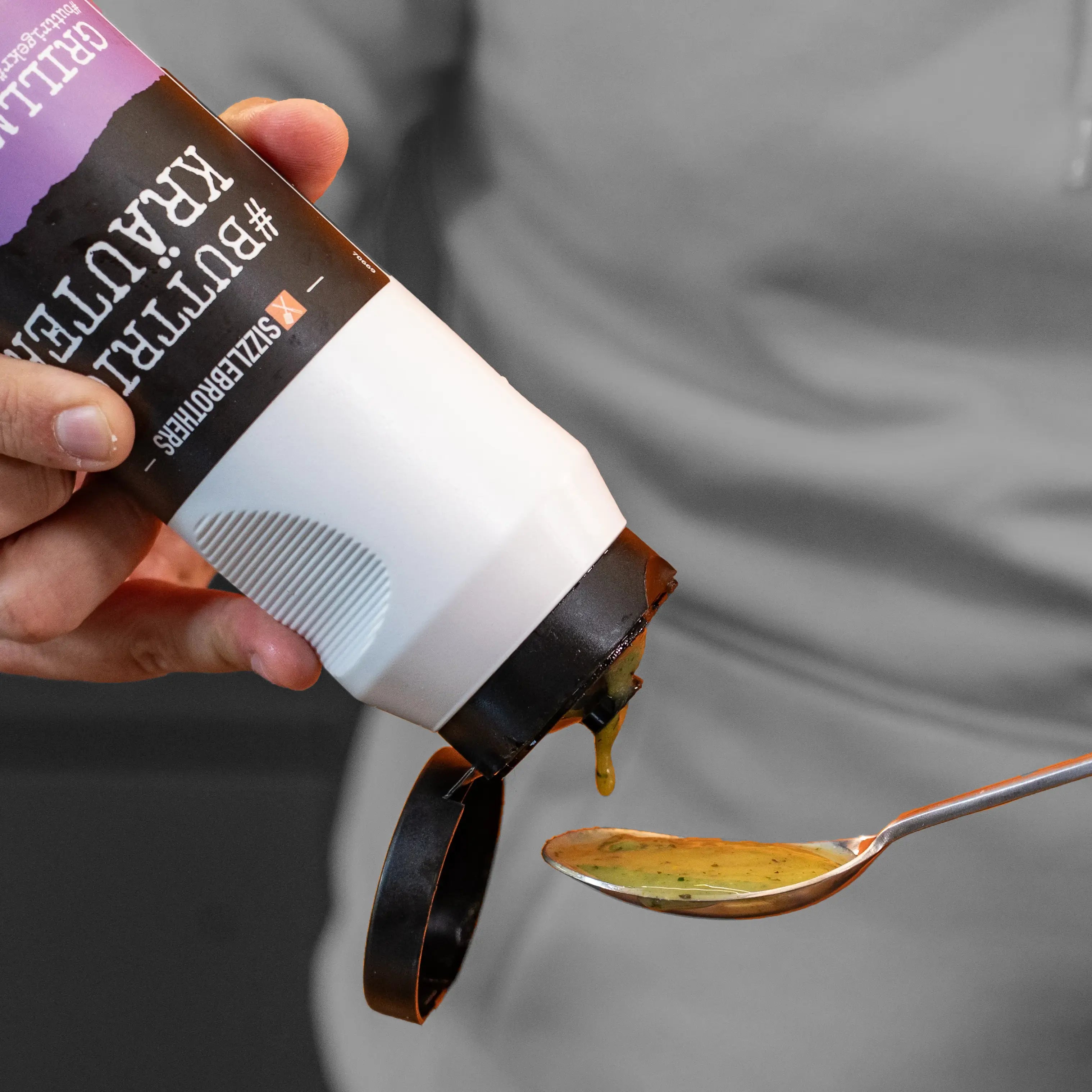 Hand presst grüne Sauce aus großer Flasche in einen Löffel.