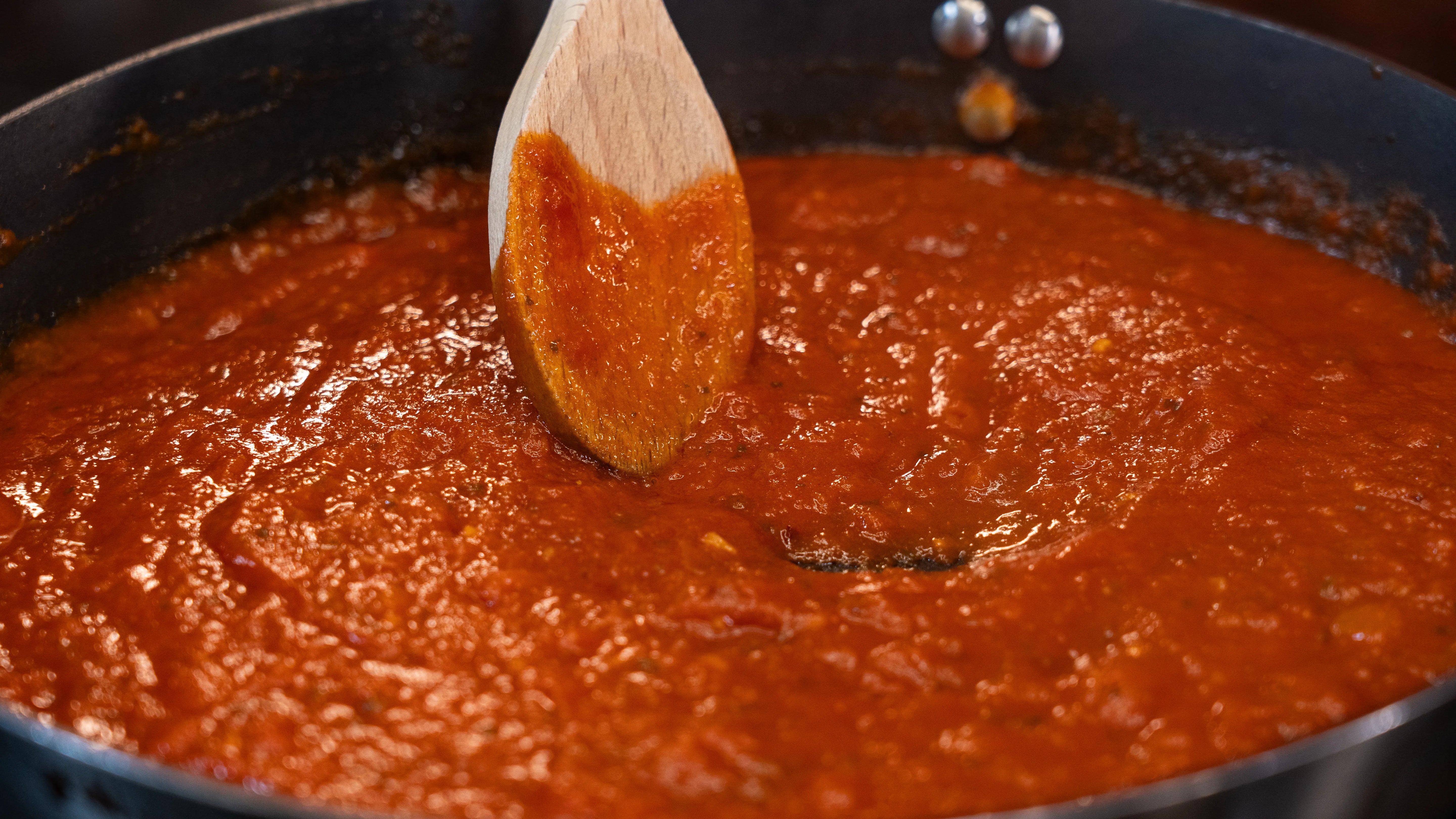 Tomatensauce in einer Pfanne mit hölzernem Löffel in der Mitte.