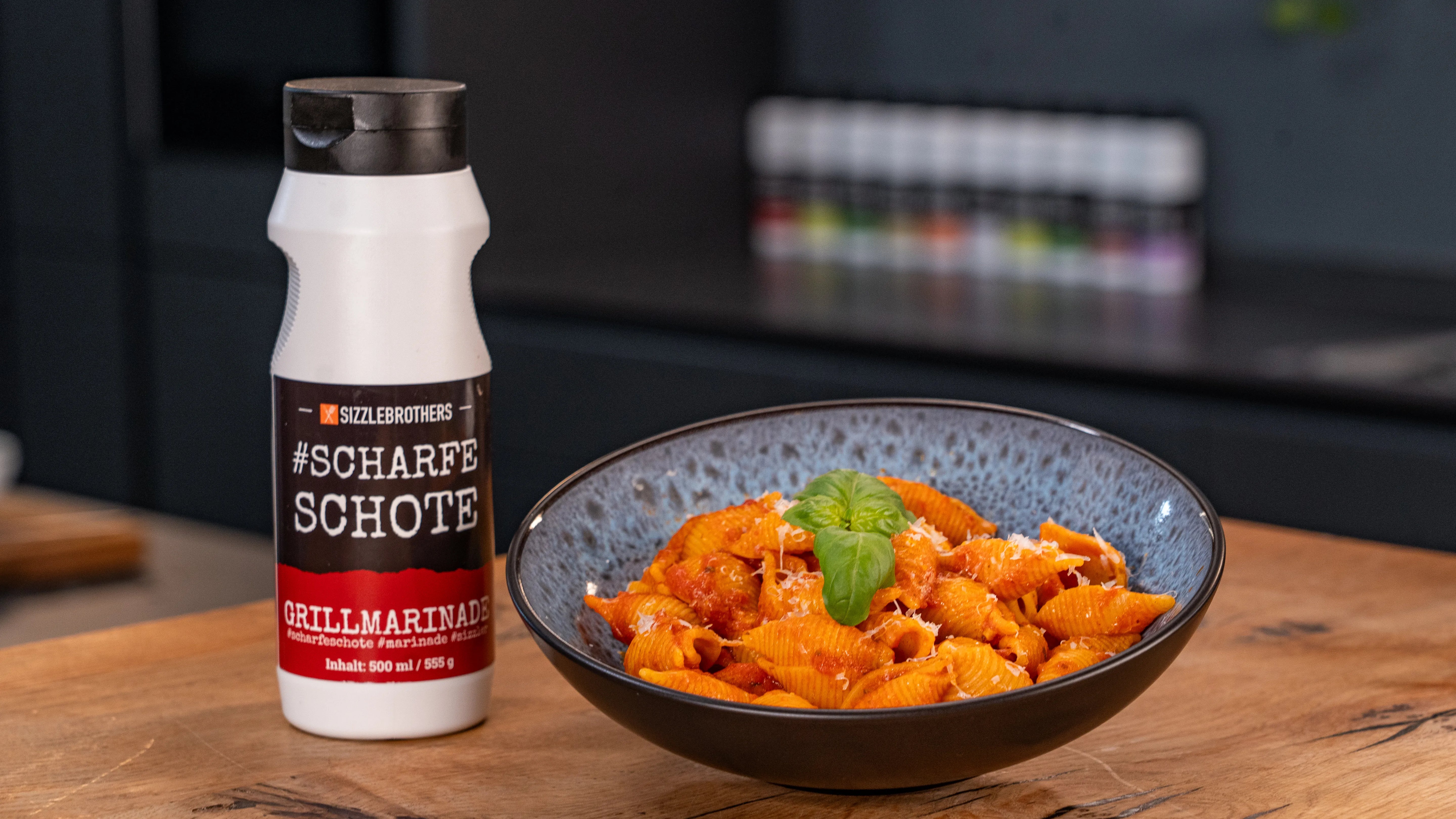 Nudeln mit roter Sauce und Basilikum neben einer Flasche "#SCHARFE SCHOTE".