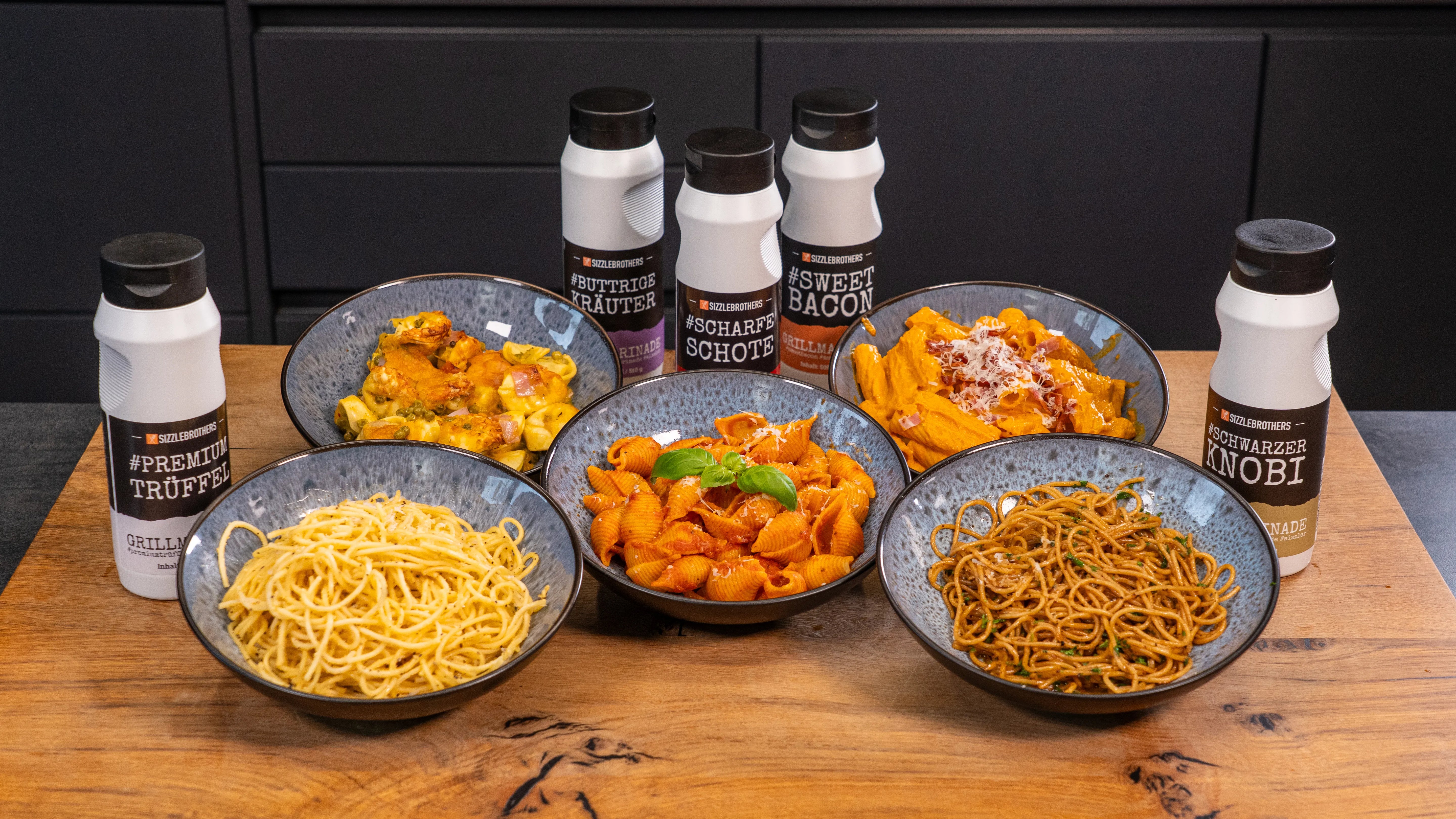 Sechs Schalen Pasta mit verschiedenen Soßen und Gewürzen.