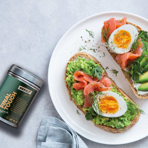 Avocado-Toast mit Ei und Lachs auf weißem Teller, daneben Final Touch Gewürzdose.
