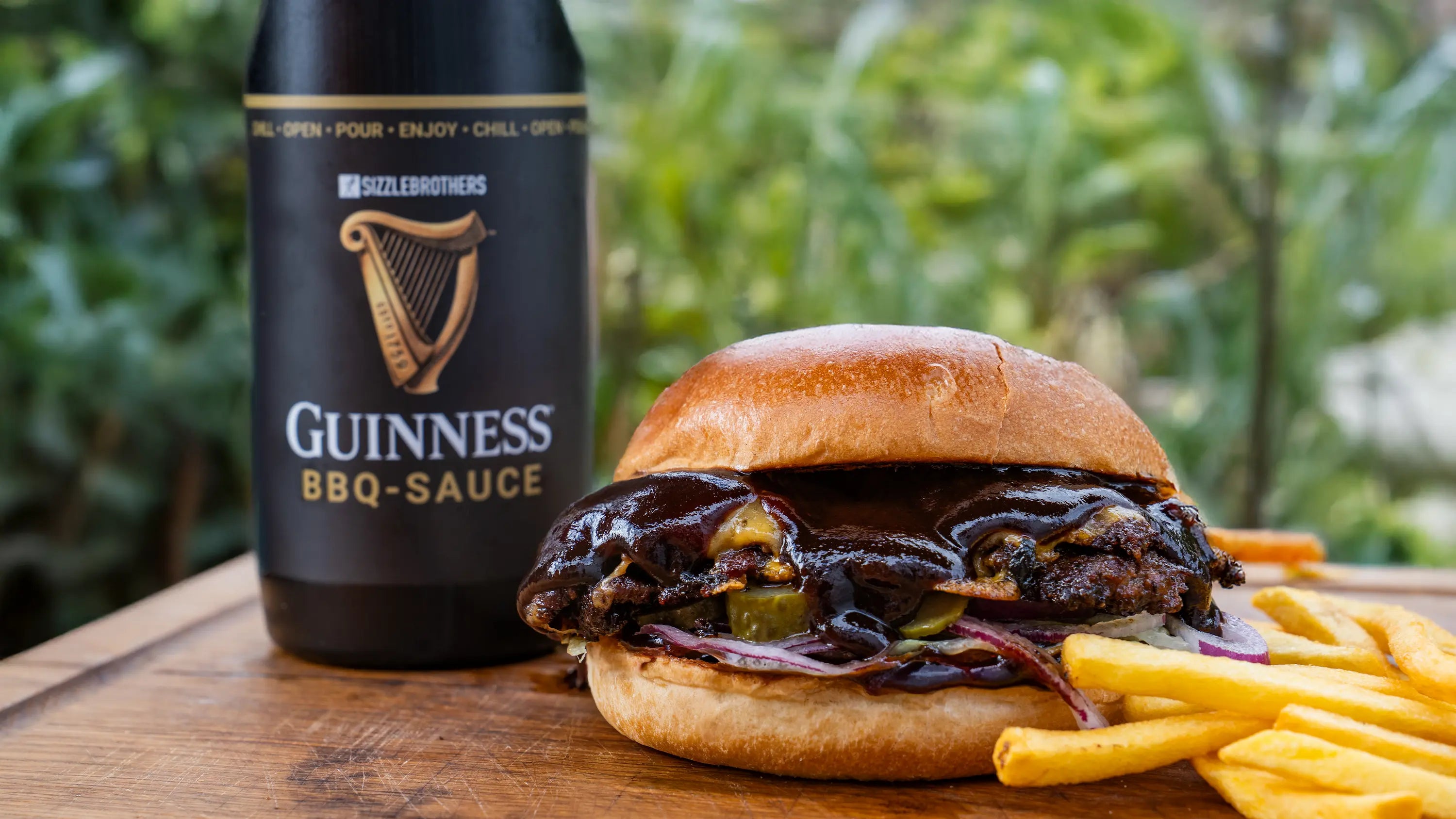 Burger mit BBQ-Sauce und Pommes neben einer Guinness BBQ-Sauce Flasche.