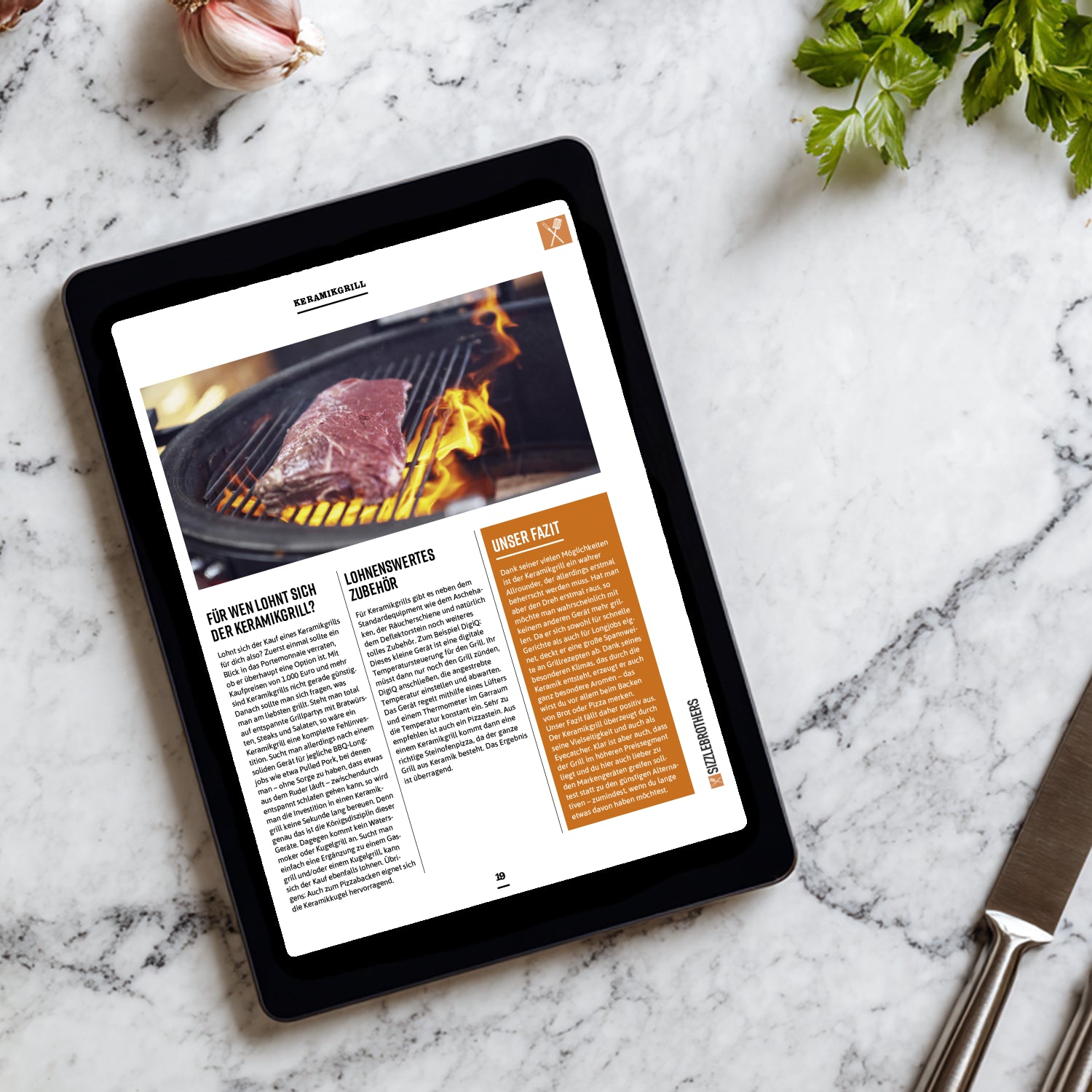 Tablet mit einem E-Book über Grills und ein Messer auf einem Marmortisch.