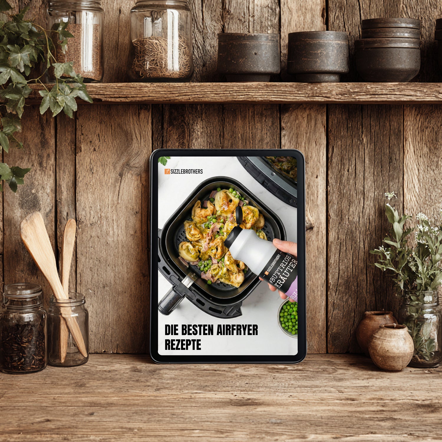 Tablet auf Holzregal in Küche, zeigt Essen in einem Airfryer und Text 'DIE BESTEN AIRFRYER REZEPTE'.