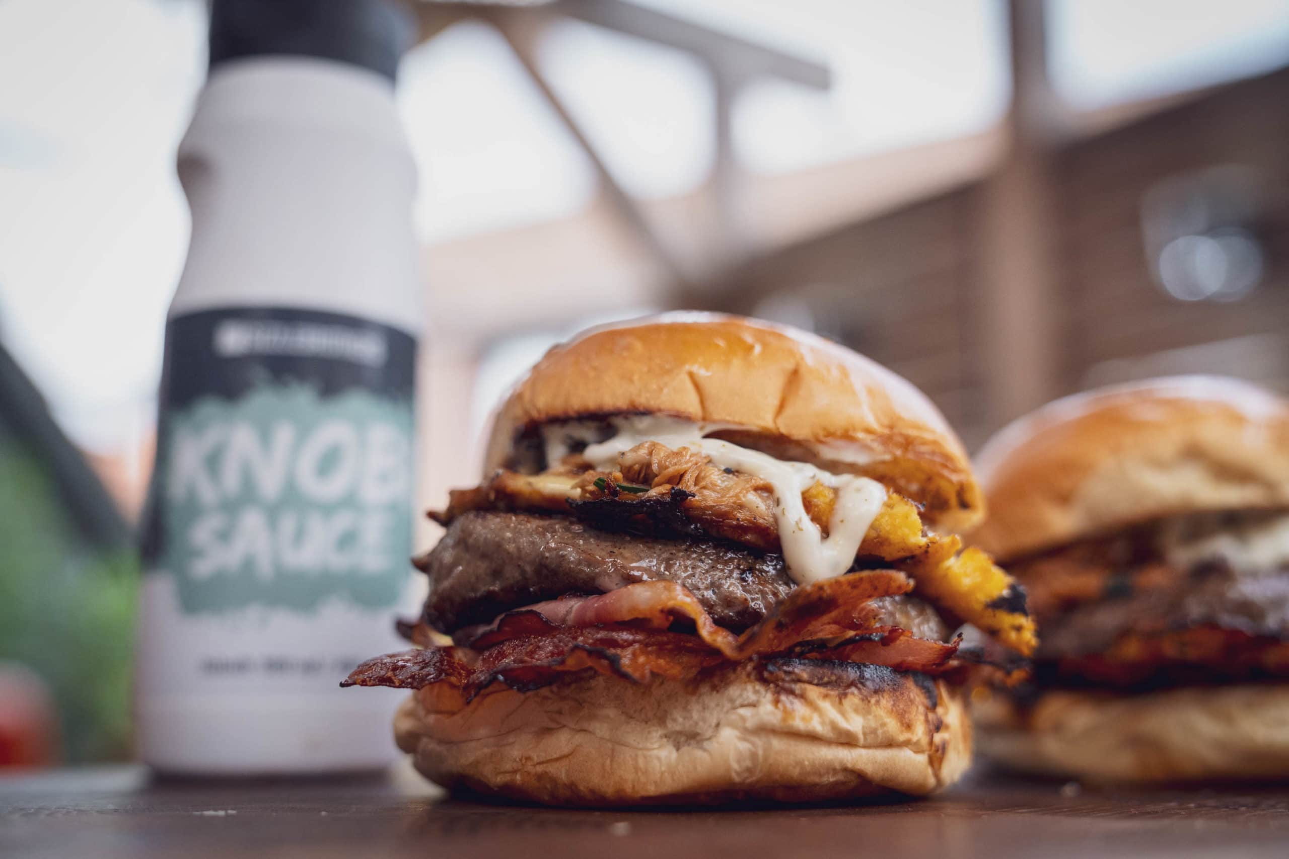 Burger mit Käse, Bacon und Sauce im Vordergrund.