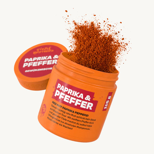 Orangene Dose mit Aufschrift 'PAPRIKA & PFEFFER', rotes Gewürz flockt heraus.