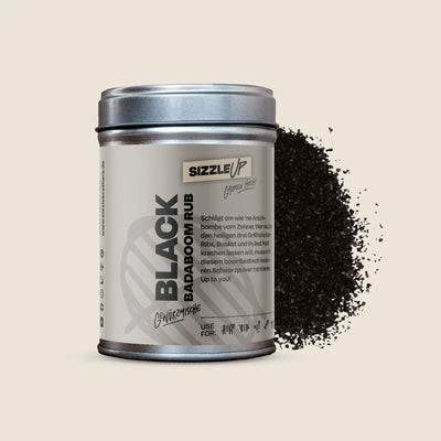 Graues Gewürzdose mit Aufschrift 'BLACK BADABOOM RUB'. Dunkle Gewürzmischung daneben.