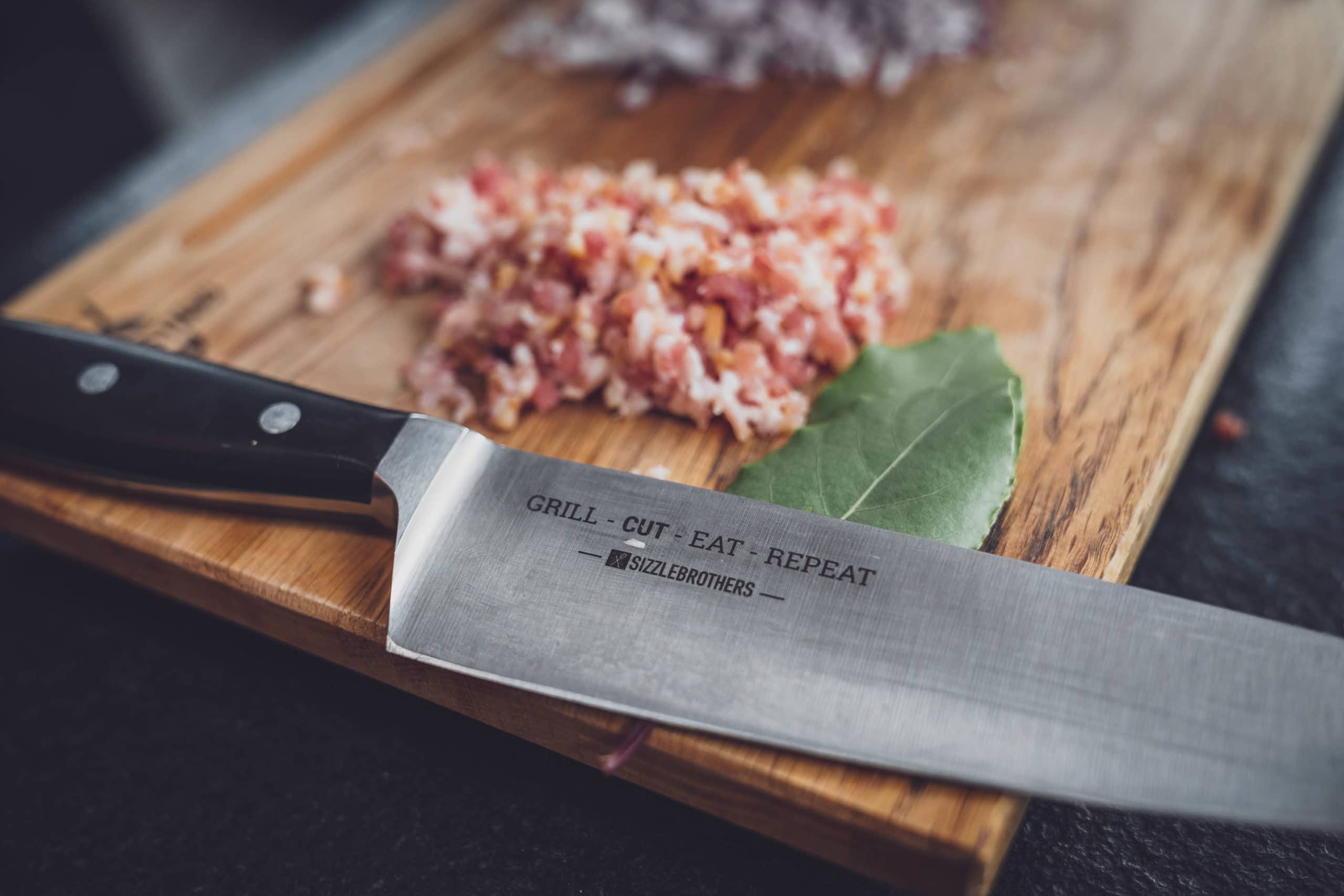 SizzleBrohters Messer mit Bacon im Hintergrund