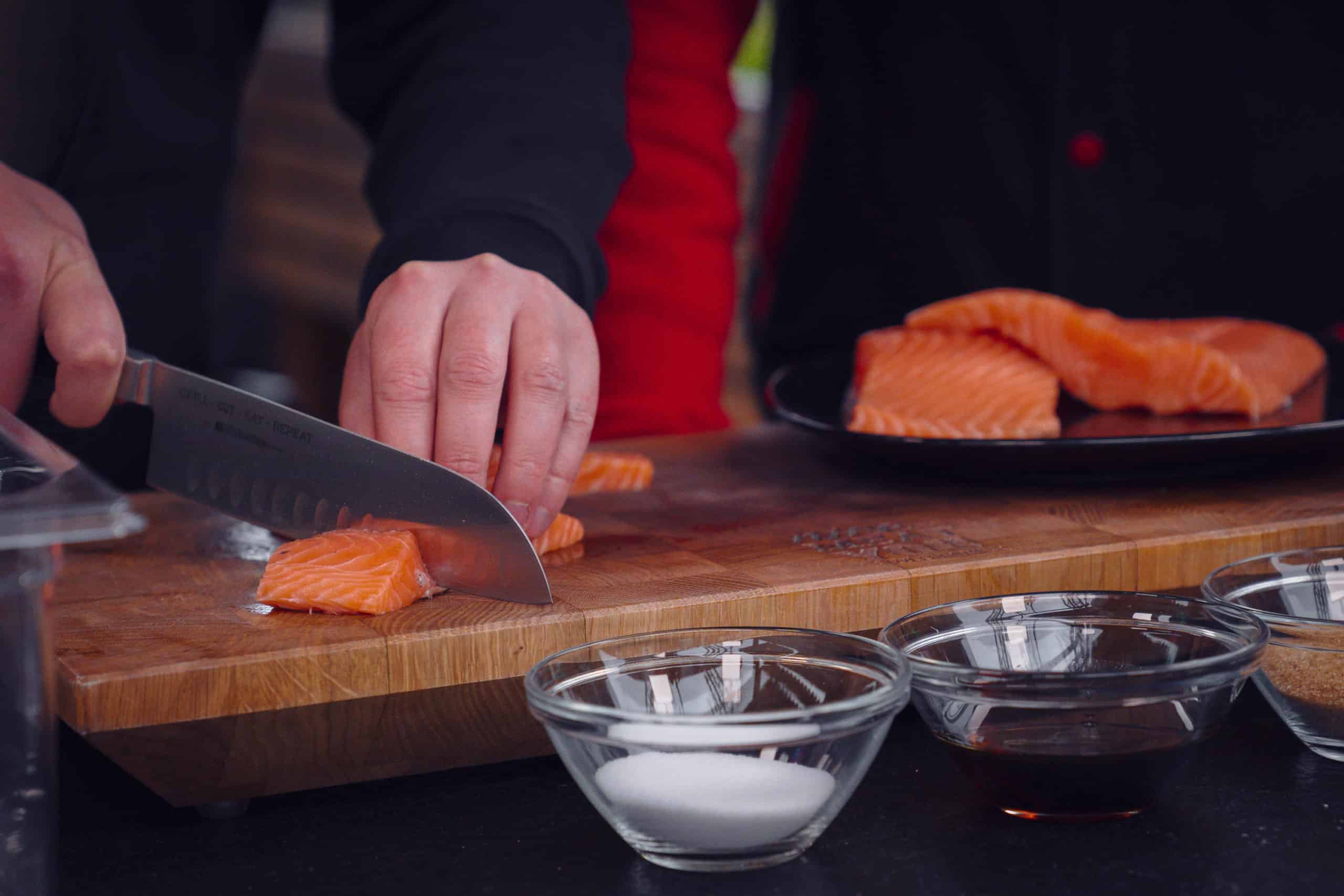 Der Lachs wird mit einem Kochmesser in Würfel geschnitten