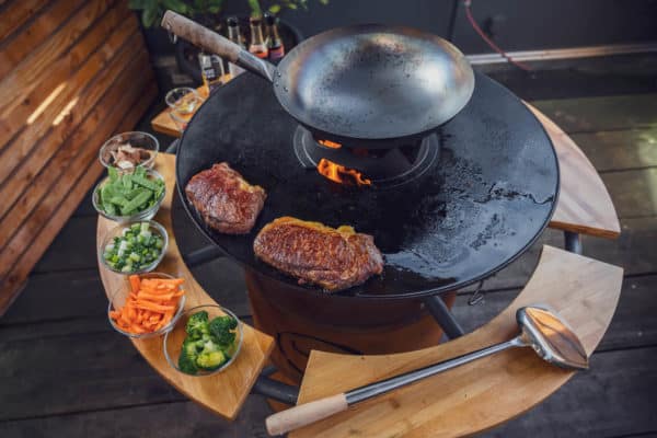 Wokgemüse und Steaks auf der Plancha der Feuertonne